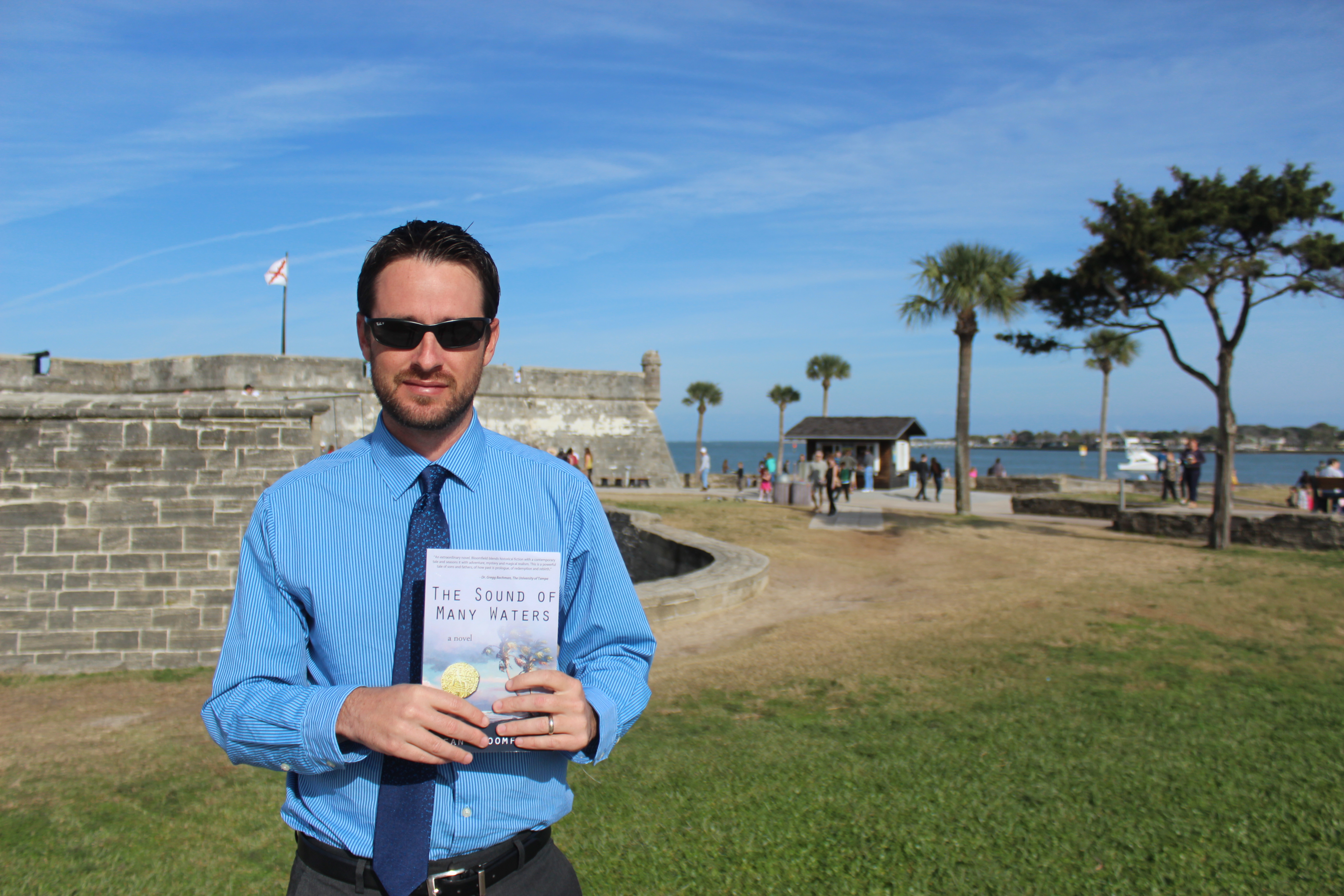 Sean Bloomfield with his novel, The Sound of Many Waters, at one of the settings in the book: St. Augustine, Florida.