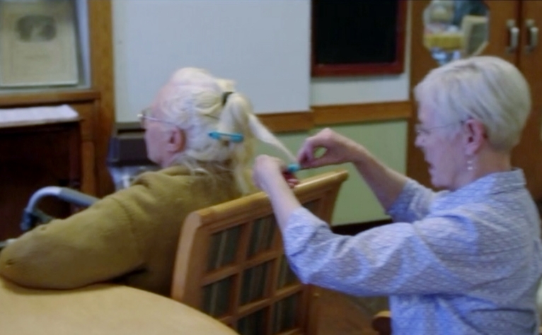 Attempting to roll the hair of a fellow Alzheimer patient in 