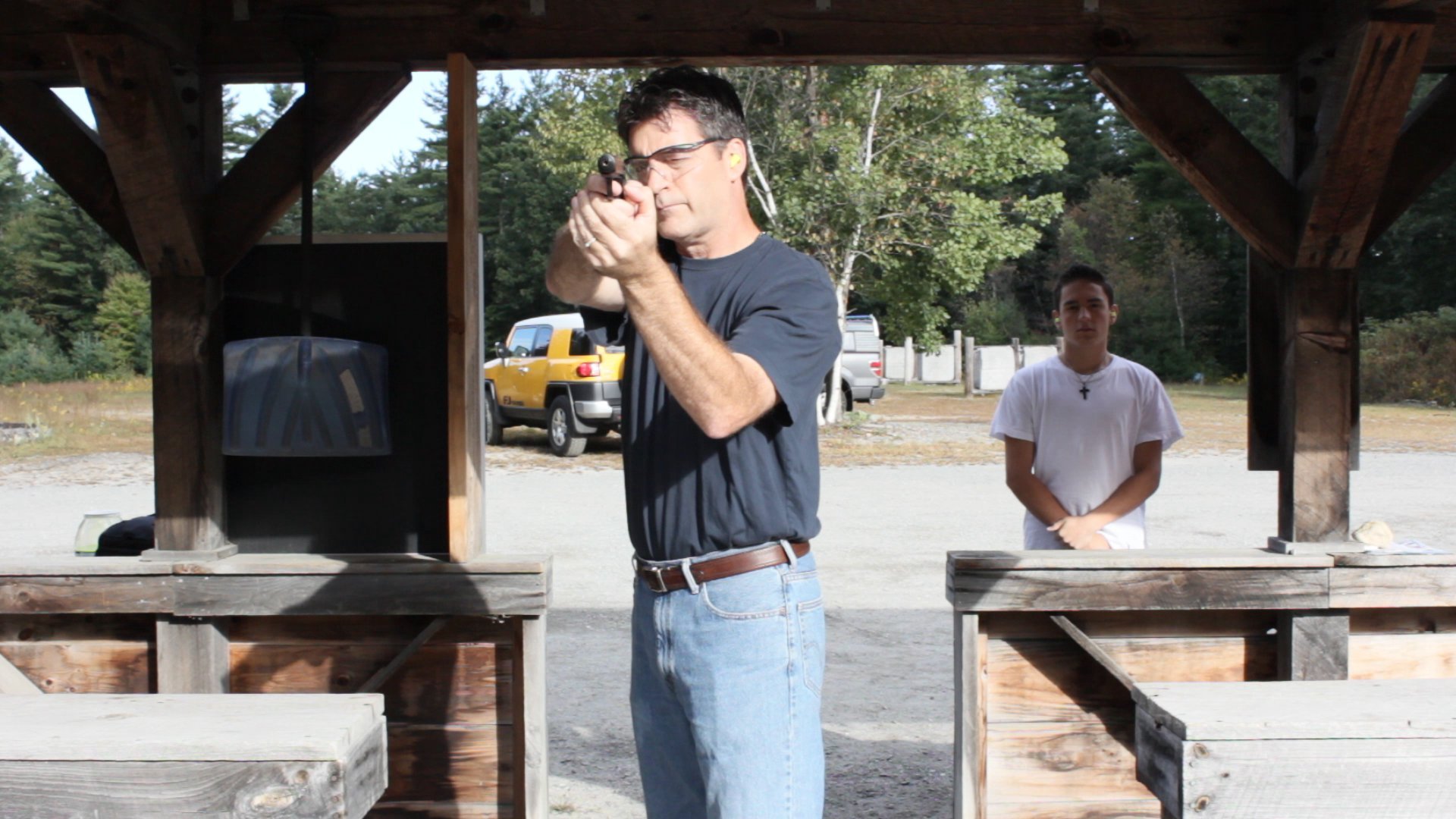 An expert marksman, Henri Miller practices at a shooting range while his son, Gary, watches.