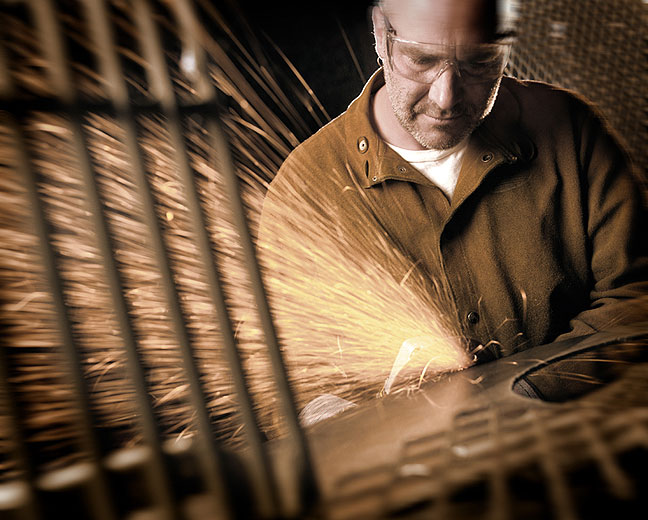 Sculptor Bruce Gray grinding a metal sculpture in his studio.