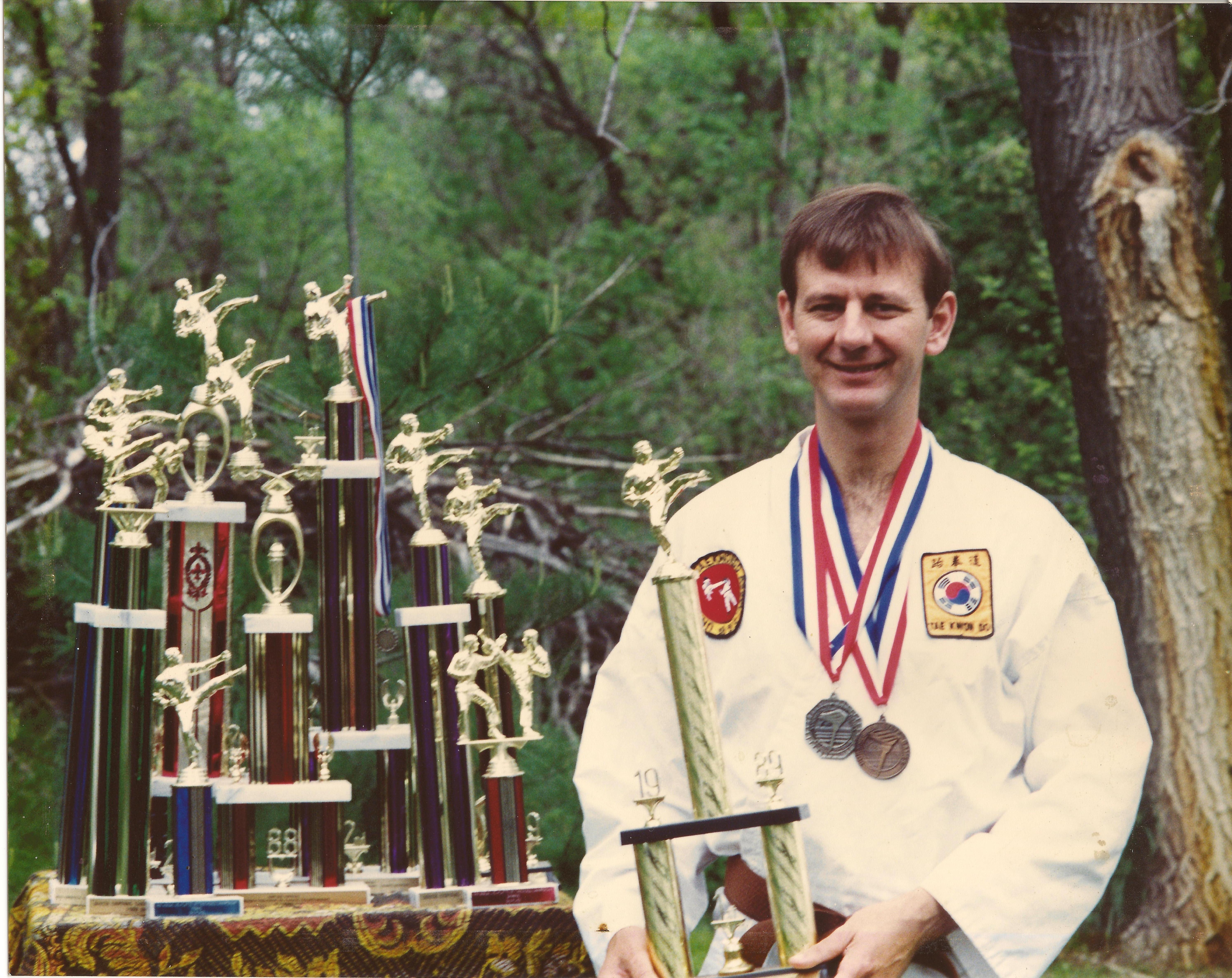 Gus Rhodes with the ten trophies which he won during the two years that he competed in Martial Arts Tournments. In the 1988 State Athletic Games he won the bronze medal for sparring and won the silver medal at the State Games the following year. He won the