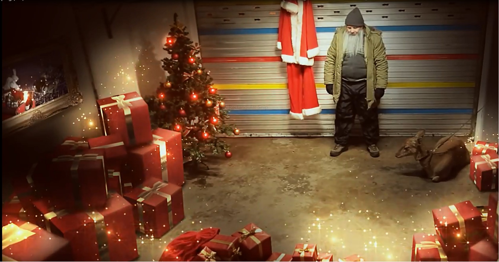 Still of Dean Dawson as the Real Santa in his garage with Rudolf for a Gift Topping commercial.