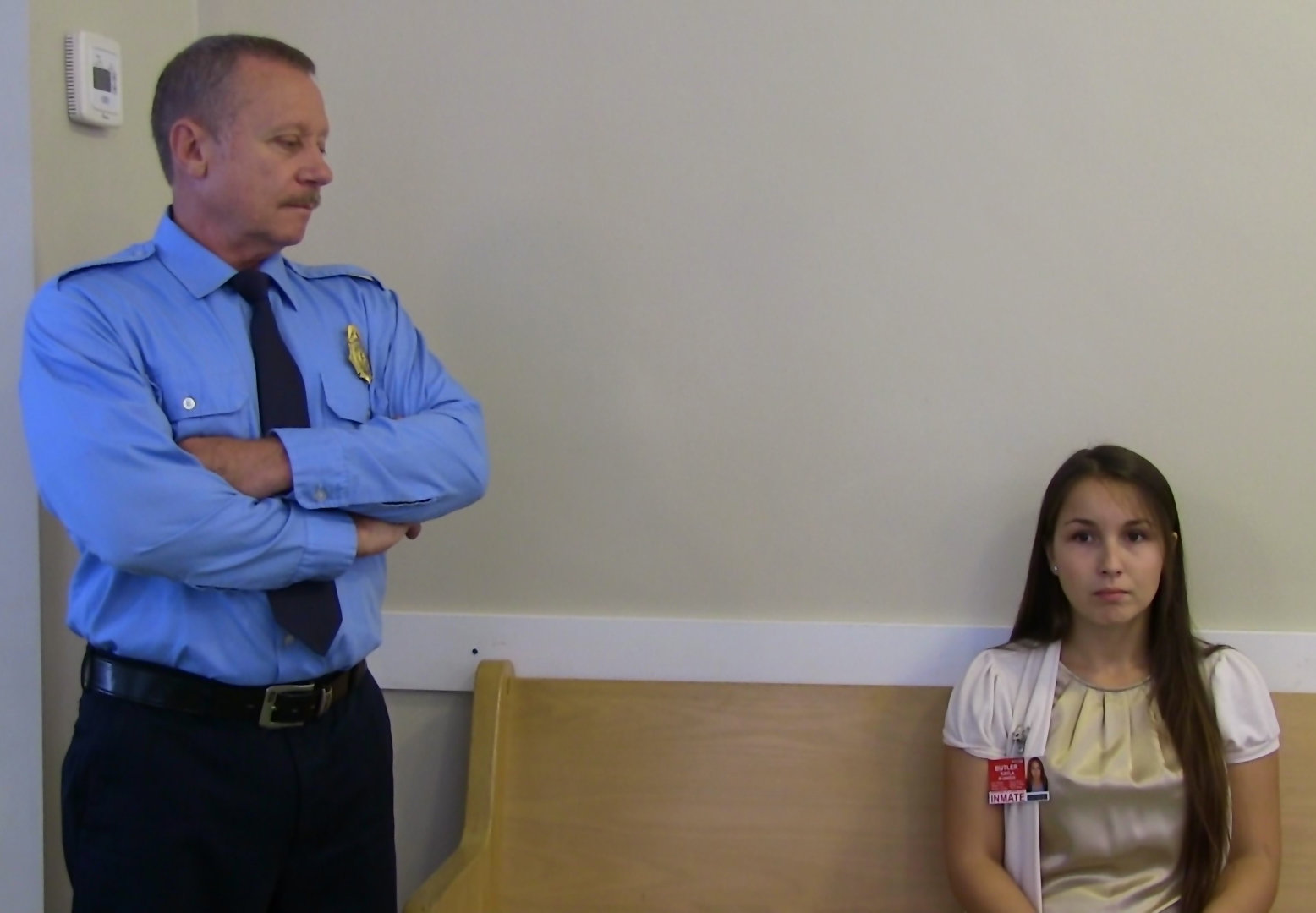 The officer (Larry Hicks) watches Kayla Butler (Jacqueline Peter) as she waits to be processed into the Lost Sheep Addiction Centre.