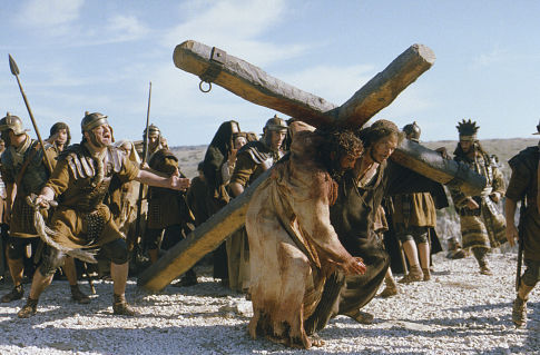 Simon of Cyrene (Jarreth Merz) helps Jesus (Jim Caviezel) carry his Cross.