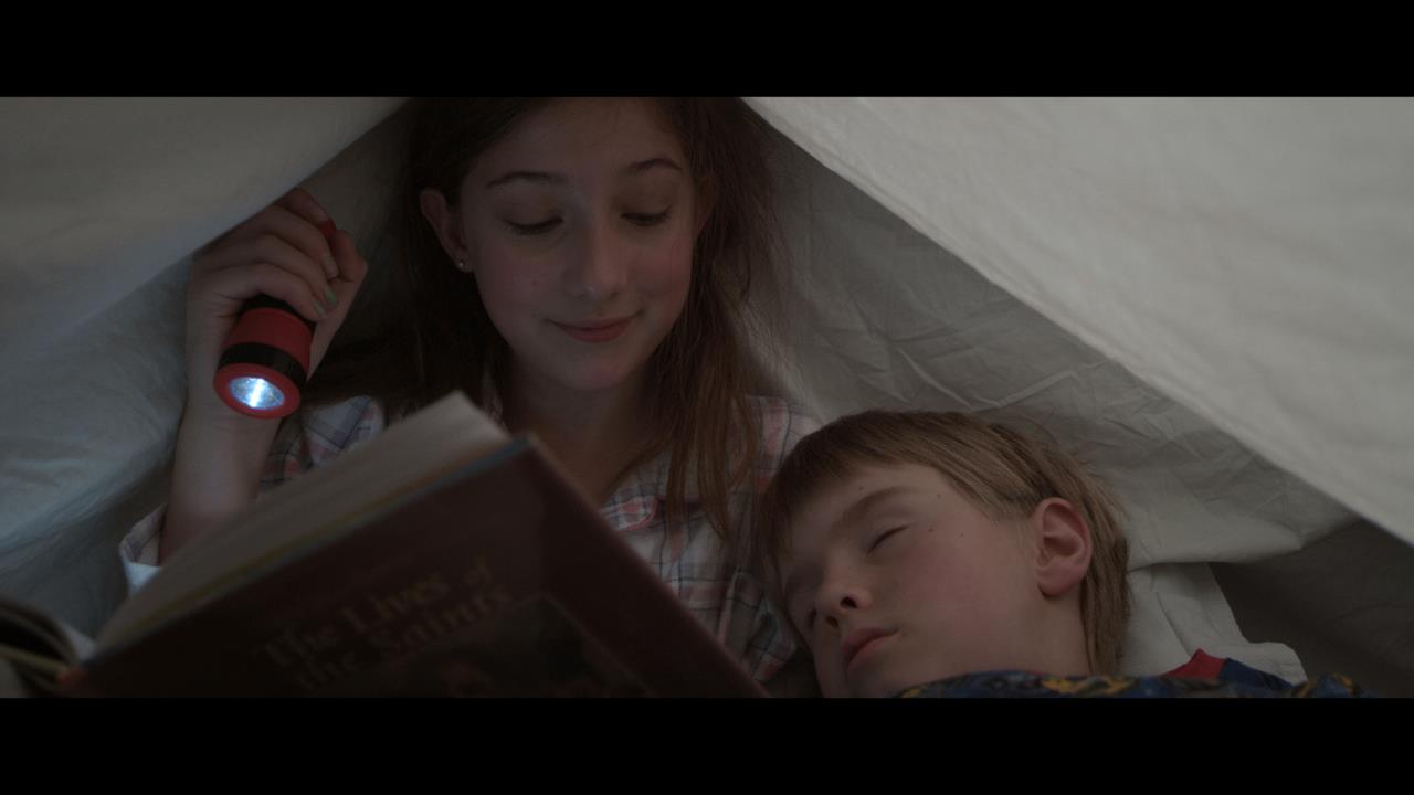 Screenshot from The Mary Contest. Adanna Avon (Mary) reading under the covers with William (Charlie Liggett.)