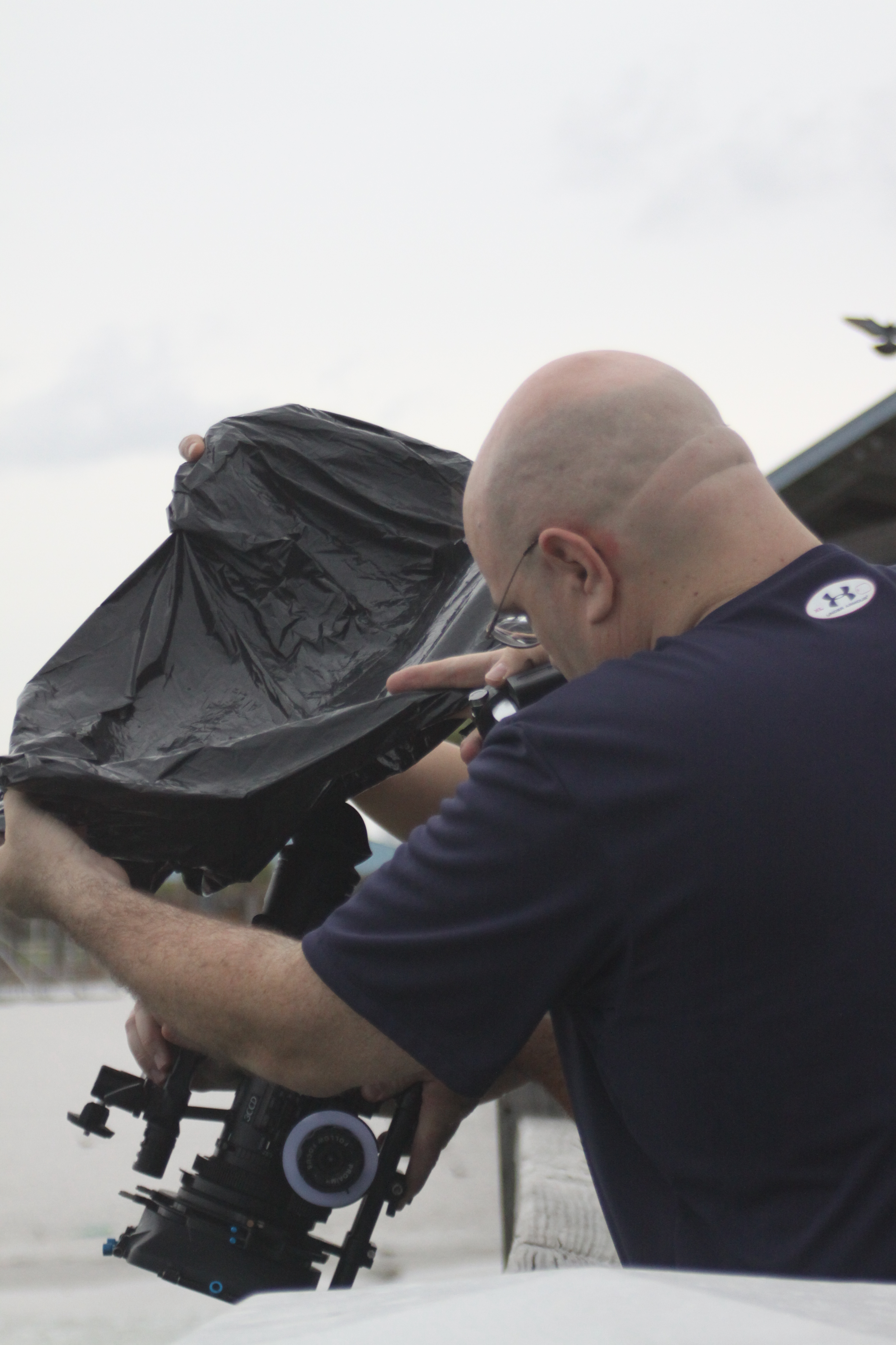 Director Donald E. Reynolds helps cover the camera from the rain as he checks out the shot fo 