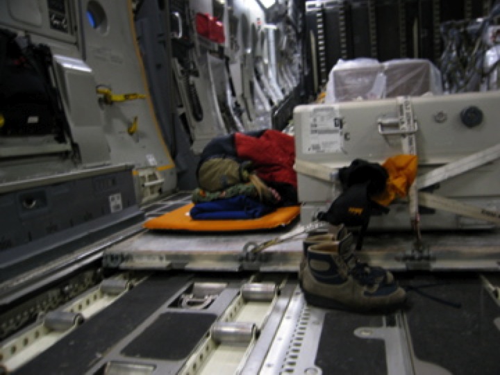 War Reporter Alex Quade sleeping next to caskets onboard Air Force cargo plane en route to Afghanistan. 2007.