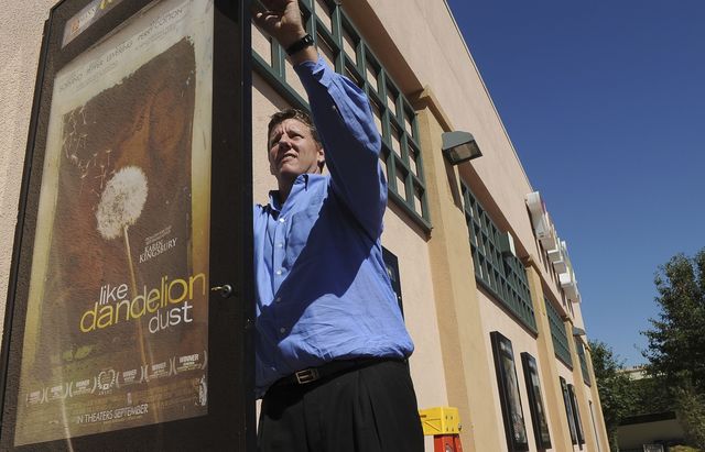 Christopher Morrow hangs a poster at the Mann Theatres at the Janss Marketplace in Thousand Oaks for the movie Like Dandelion Dust. He and his wife, Melanie Morrow, are co-executive producers of the film, which debuts locally Oct. 1.