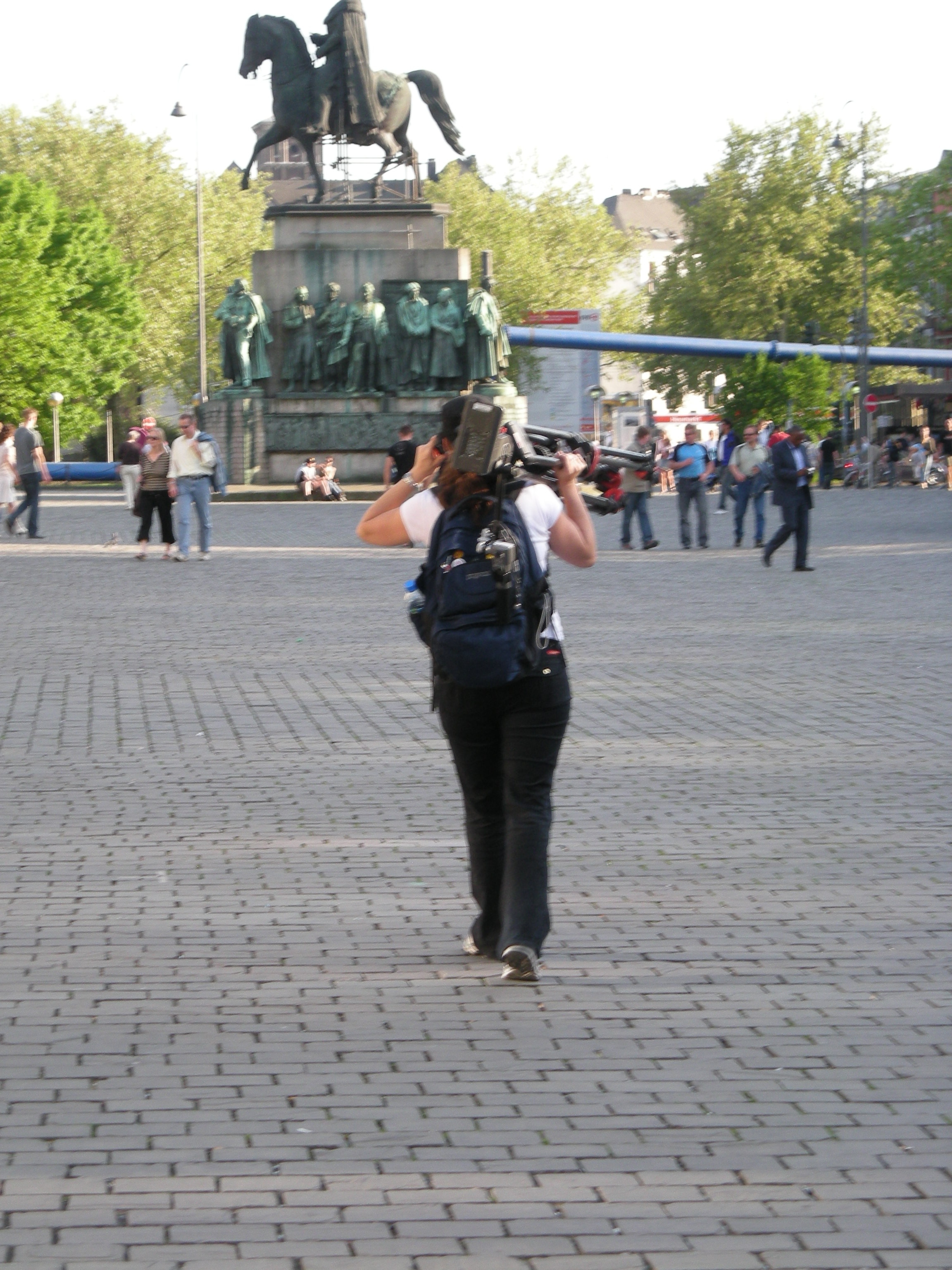 Who carries a mobile office on her back in Cologne, Germany, negotiating logistics on the phone with France while lugging sticks and wrangling the crew to stay on schedule? This chick does.