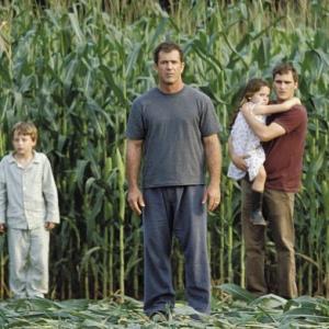 Graham Hess (Mel Gibson, center left), along with his son, Morgan (Rory Culkin, left), his daughter, Bo (Abigail Breslin, center right), and his brother, Merrill (Joaquin Phoenix, right), investigate the strange occurrence.
