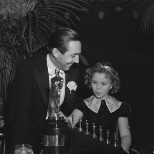 Walt Disney receives one statuette and seven miniature statuettes from Shirley Temple for Snow White and the Seven Dwarfs at the 11th Academy Awards