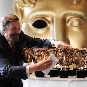 Stephen Fry poses for a photocall to buff the masks ahead of hosting the EE British Academy Film Awards 2013 at BAFTA on January 4, 2013 in London, England.