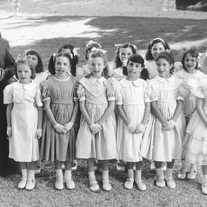 Respendent in their party dresses, Madeline (Hatty Jones, front row, far left) and her classmates attend Pepito's birthday party with the help of gift-toting Miss Clavel (Frances McDormand, far left).