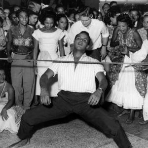 The King of Calypso Harry Belafonte limbos as a crowd cheers in 1965