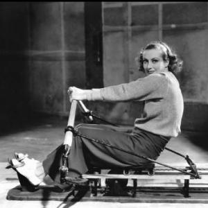 Joan Crawford exercising on a rowing machine MGM 1933
