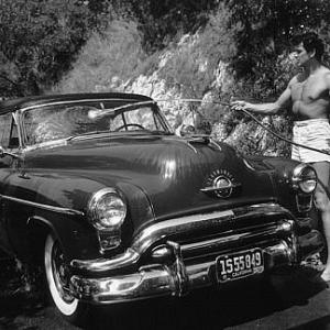Rock Hudson washing his 1952 Oldsmobile outside of his Hollywood Hills Home