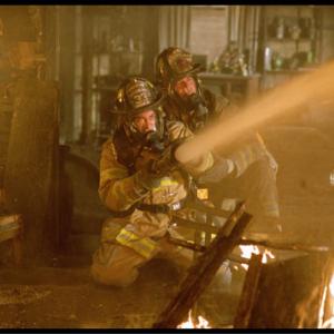 Captain Mike Kennedy (John Travolta, right) shows rookie firefighter Jack Morrison (Joaquin Phoenix, left) the ropes during his first fire.