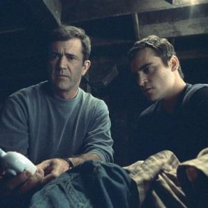 A baby monitor provides a message from above for Graham (Mel Gibson, left) and his brother, Merrill (Joaquin Phoenix, right).