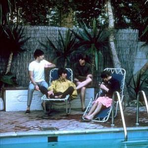 The Beatles Paul McCartney George Harrison John Lennon Ringo Starr relax along the poolside as Ringo fiddles with his camera 1964
