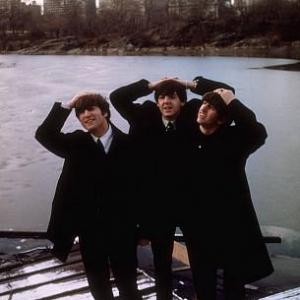 The Beatles John Lennon Paul McCartney Ringo Starr with their hands on top of their heads and the city as their background 1964