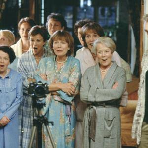 The women of Knapely (left to right, front row: Lesley Staples, Angela Curran, Julie Walters, Rosalind March, Penelope Wilton, Annette Crosbie. left to right, back row: Janet Howd, Celia Imrie, Georgie Glen, Linda Bassett) prepare to bare all for their photographer, Lawrence (Philip Glenister, right).