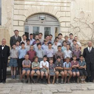 The boys of Fond De LEtang school Adults standing L to R are Francois Berleand who portrays Rachin Kad Merad who portrays Chabert and Gerard Jugnot who portrays Clement Mathieu