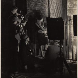 Edwin Greenwood wearing hat kneeling in profile directing a film