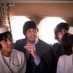 The Beatles, (Paul McCartney, George Harrison) on the plane with flight attendants, 1964