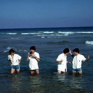 The Beatles, (Ringo Starr, George Harrison, John Lennon, Paul McCartney) playing in the water.