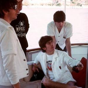 The Beatles (Ringo Starr, John Lennon, George Harrison, Paul McCartney) on board a boat.