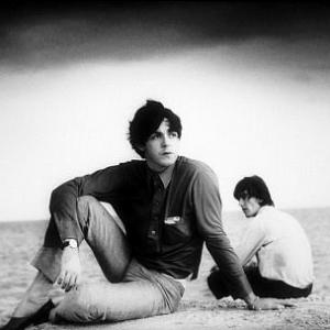 The Beatles Paul McCartney and George Harrison sitting on the sands c 1964