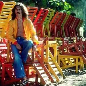 George Harrison in Acapulco posing with colorful wooden lounge chairs January 1977