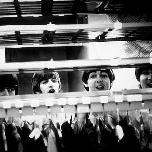 The Beatles George Harrison Ringo Starr Paul McCartney John Lennon peering through a clothes rack in Cleveland OH September 15 1964
