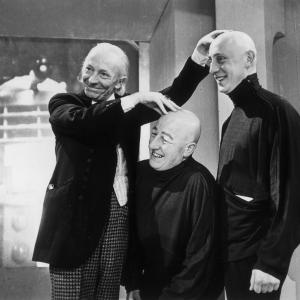 1965: William Hartnell (1908 - 1975), the first incarnation of TV's Dr Who, feels the hairless pates of two ticklish co-stars. They are appearing as the Teknix, bald mutated humans employed in Space Security.