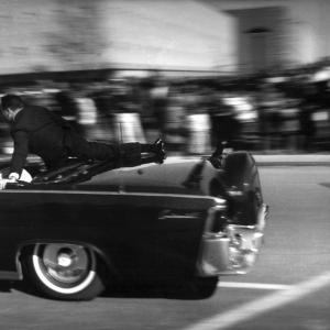Secret Service Agent Clint Hill uses his body to shield President and Mrs Kennedy from assassins bullets on 112263 as car reaches speeds of 80 mph