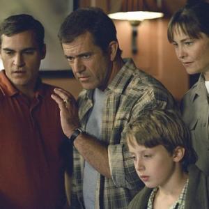Graham (Mel Gibson, center), flanked by his brother, Merrill (Joaquin Phoenix, left), Officer Paski (Cherry Jones, right), and his son, Morgan (Rory Culkin, foreground), soon find that they are not alone - that crop signs are appearing all over the world