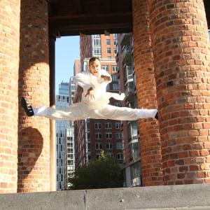 Sifu Lyn is flying performing a jump split kick.