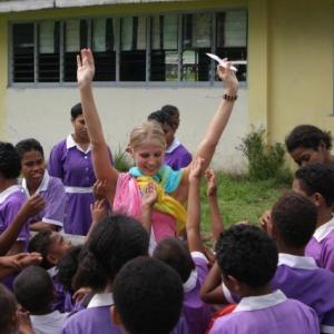 Fiji pilot Blue handing out stickers to children at a local school