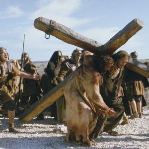 Simon of Cyrene (Jarreth Merz) helps Jesus (Jim Caviezel) carry his Cross.