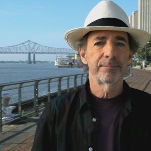 Harry Shearer director of The Big Uneasy in New Orleans on the bank of the Mississippi River with the Pontchartrain Expressway in the background
