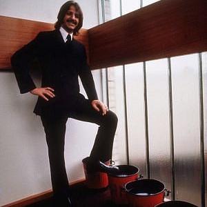 Ringo Starr in a suit resting his leg on a pail. c. 1969