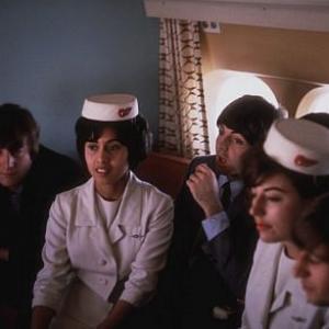 The Beatles, (John Lennon, Paul McCartney, George Harrison, Ringo Starr) in the plane with the stewardess.