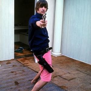 The Beatles Ringo Starr playing with his gun pointing at the photographer 1964