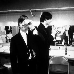 The Beatles (Ringo Starr and Paul McCartney inside their dressing room. Ringo with a cup covering his left eye) c.1964