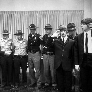 The Beatles George Harrison Ringo Starr  Paul McCartney in Indianapolis with officers as Ringo and Paul salute c 1964