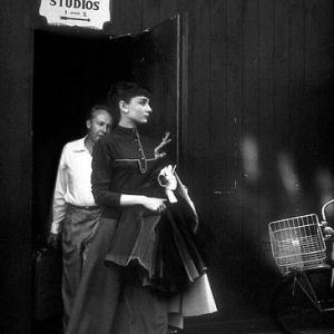331121 Audrey Hepburn helped by photographer Bud Fraker leaving photo gallery C 1956