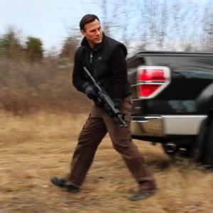 Jeff Corazzini still shot playing The Protector searching for bad guy hiding in a hunting cabin