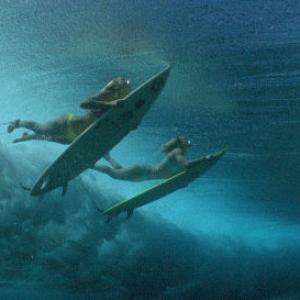 Layne Beachley foreground and Rochelle Ballard duck their boards under a big wave in Tahiti