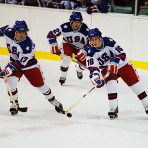 Jack O'Callahan (Michael Mantenuto, left), Buzz Schneider (Billy Schneider, center), and Mark Pavelich (Chris Koch, right) chase the puck.