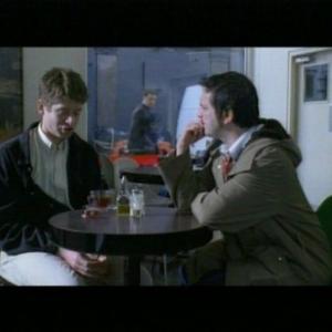 Anthony (James Macartney) meets William (Tom Wontner) at a cafe to discuss 0800Friend.com, whilst Rob (Mem Ferda) looks on through the window.